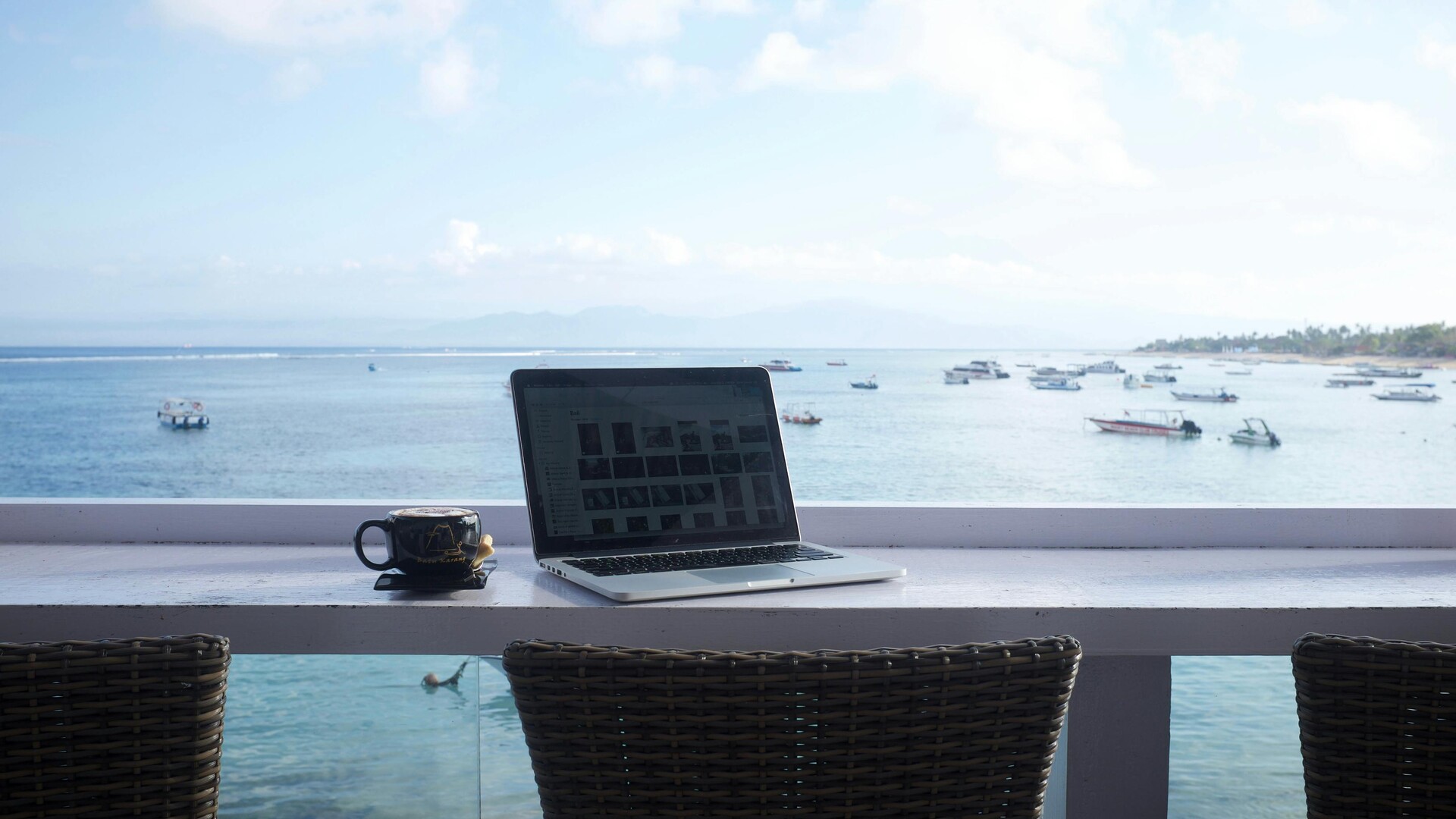Work & Travel - Laptop workspace with ocean view from modern office